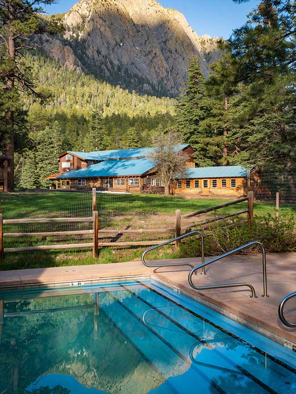 Swimming pool steps with cabins and cliffs in background