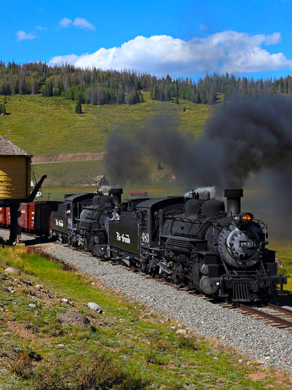 Cumbres & Toltec Scenic Railroad steam train with black smoke in a meadow