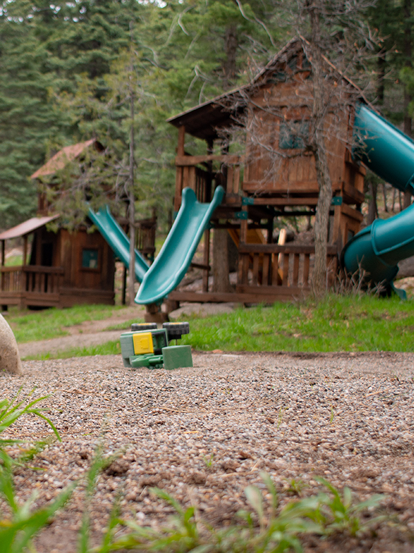 Wooden cabins with turquoise blue slides and toy truck in foreground
