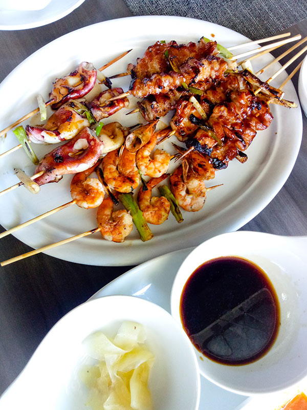 Shrimp and meats and veggies on skewers with sauce and ginger