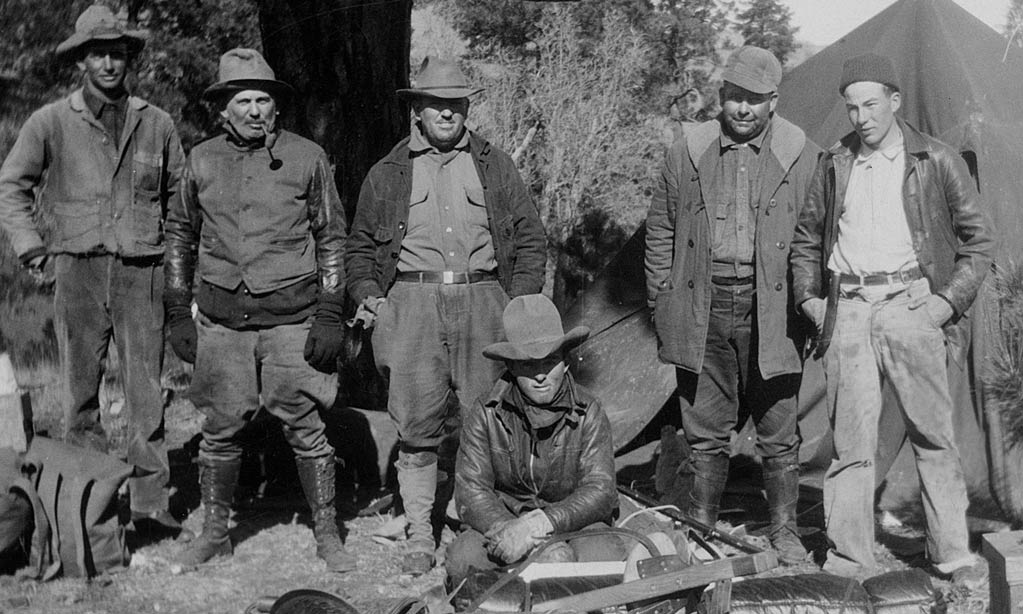 6 men in outdoor gear in grainy black and white historic photo from the 1920s
