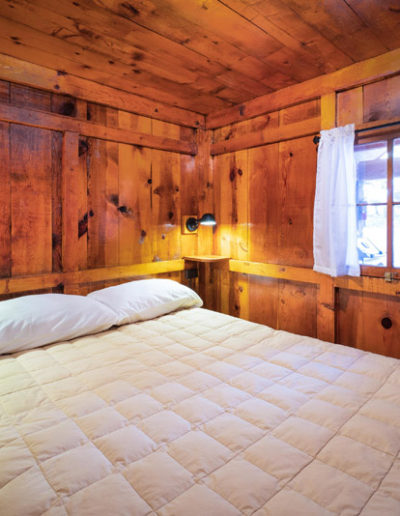 Bedroom with bed and window, wooden walls and ceiling