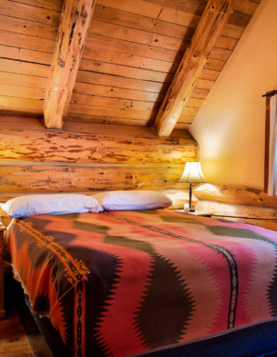 Bed in log cabin bedroom with 2 nightstands and window