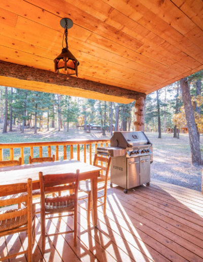 Deck view with table and grill overlooking pine trees and other cabins