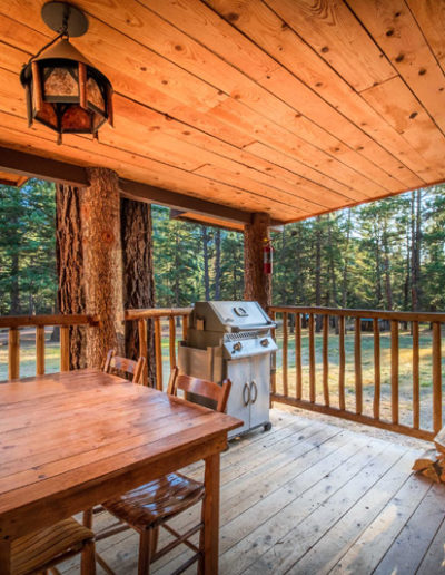 Cabin exterior with deck, table, grill, and firewood