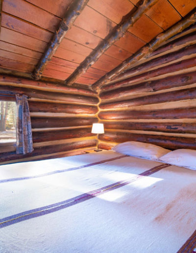 Bedroom with king bed and white blanket, log wood walls and ceiling