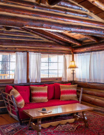 Living room with red couch, coffee table, log beam walls and ceiling wood floor