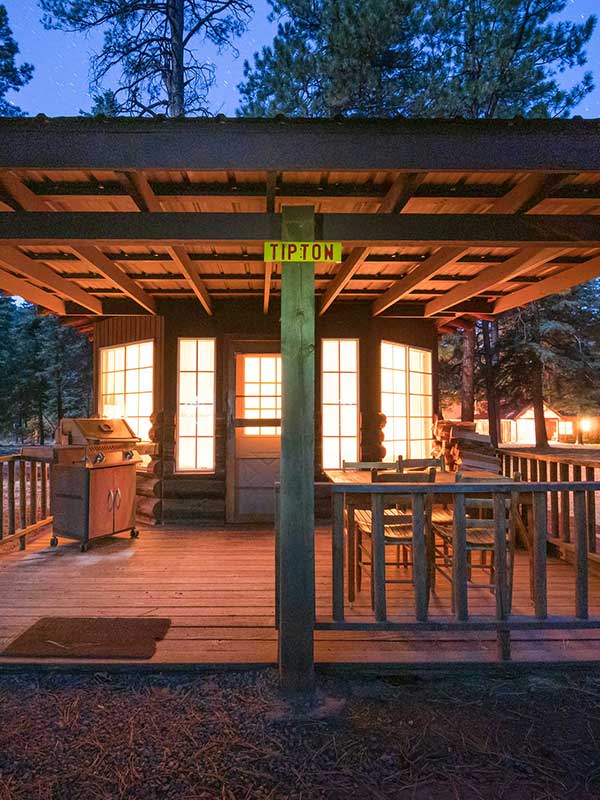 Exterior of cabin deck at dusk with light shining from bay windows