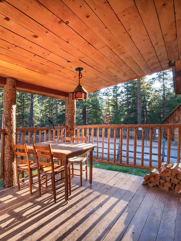 Cabin patio porch with wooden ceiling, wooden chairs and table, firewood