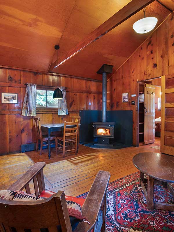 Interior of cabin with wood burning stove, table, chairs and wooden walls, ceiling and floors