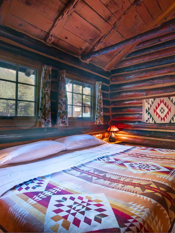Bed with native blanket design log cabin walls and ceiling