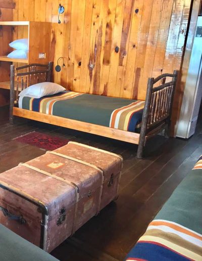 Twin bed in log cabin with antique chest as coffee table