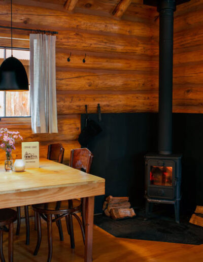 Log cabin interior with table, chairs and wood burning stove in the corner