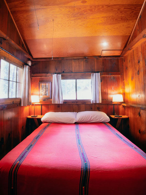 Wood cabin bedroom with bed with red pendleton blanket
