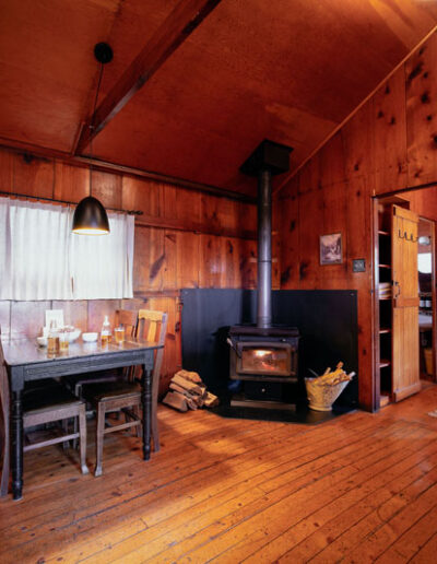 wood cabin living space with table and chairs and a black wood burning stove
