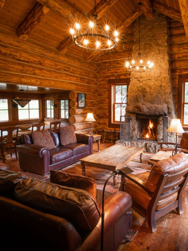 Log cabin large living room with couches, chairs, coffee table and stone fireplace