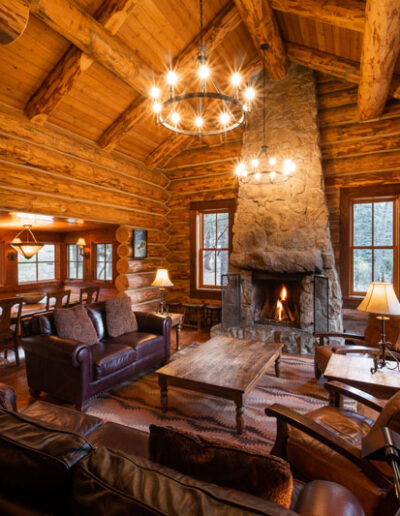 Log cabin large living room with couches, chairs, coffee table and stone fireplace