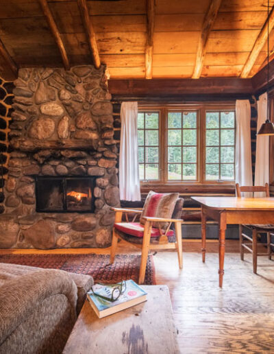 Ponderosa Cabin living room with log cabin walls, couches, chairs, and a stone fireplace