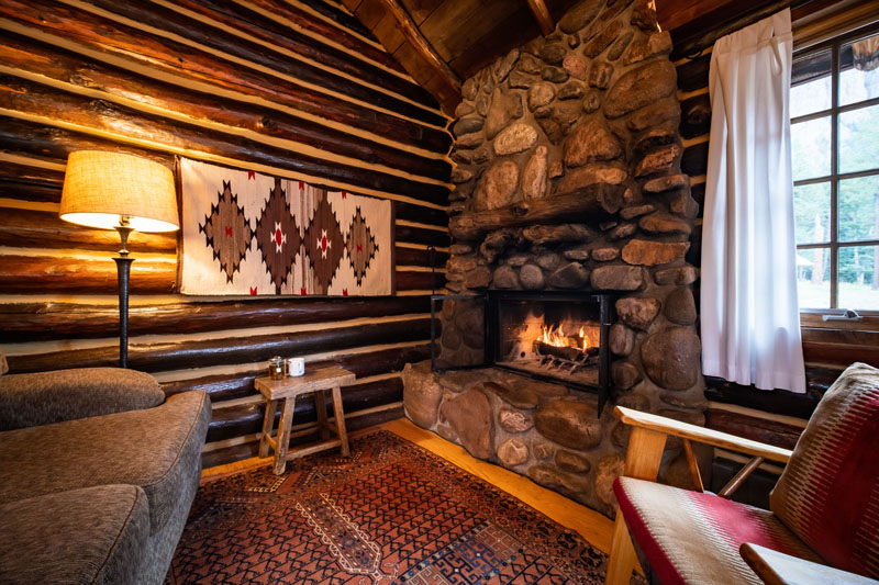 Ponderosa Cabin living room with log cabin walls, couches, chairs, and a stone fireplace