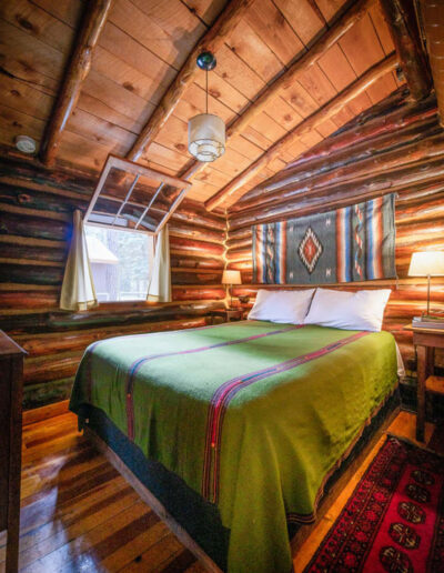 Tipton bedroom with log cabin walls and a green pendleton blanket on a bed
