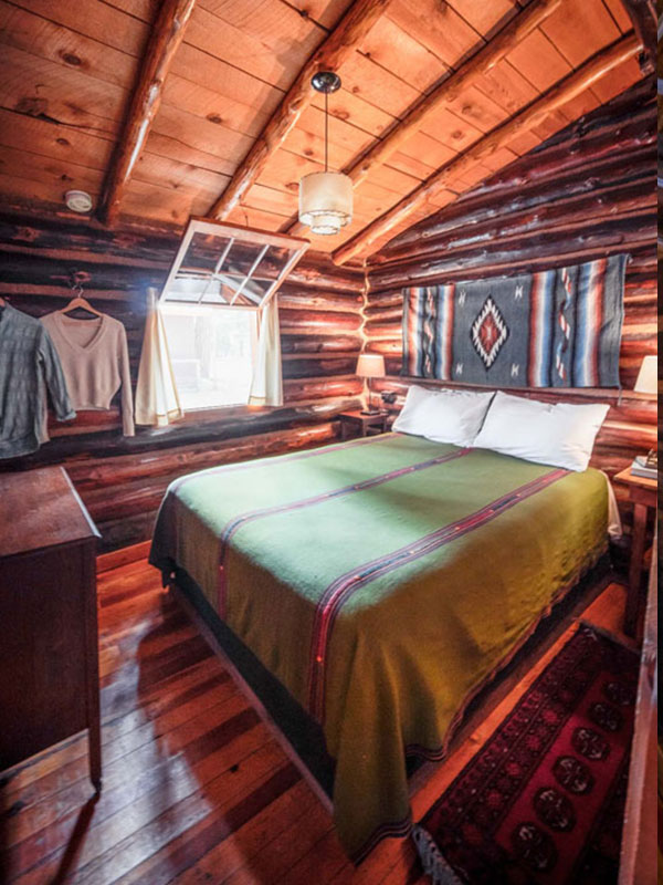 Tipton bedroom with log cabin walls and a green pendleton blanket on a bed
