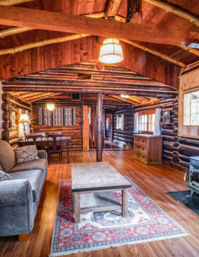 Tipton cabin living room with couches, coffee table, chairs and a black wood burning stove