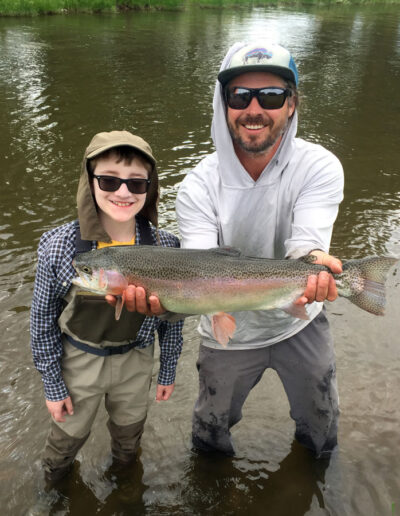 Man and child holding rainbow trout in the river