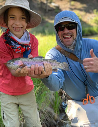 Man and boy holding rainbow trout in the river
