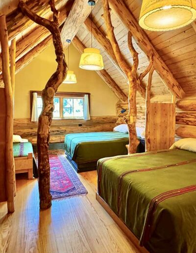 Log cabin interior with 2 Queen and 1 Twin Bed and wooden walls, ceiling and floors
