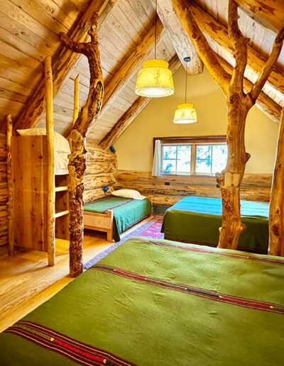 Log cabin interior with 2 Queen and 1 Twin Bed and wooden walls, ceiling and floors