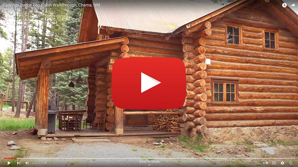 Exterior of a 2-story log cabin with a YouTube play button